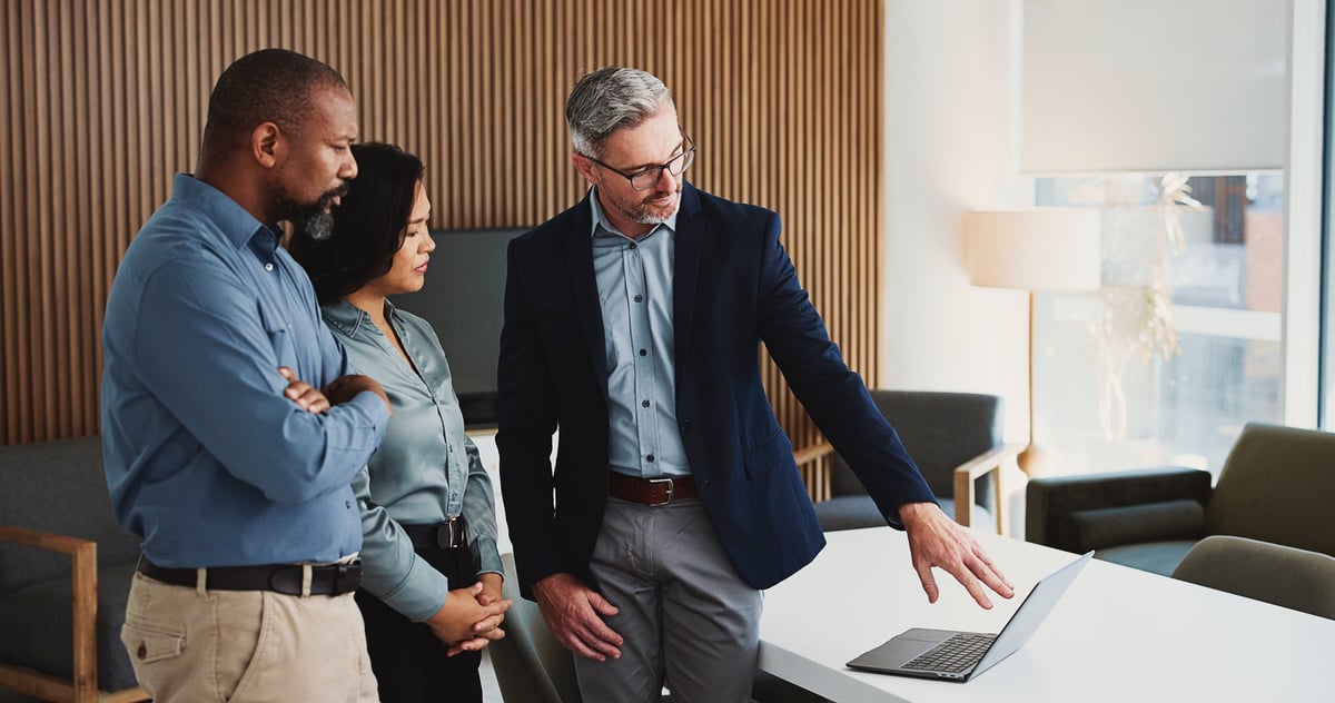 Team collaborating around a laptop in an office